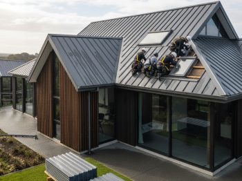 Architectural home with specialists performing roof repair in Auckland on metal roofing.