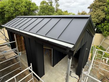 Small outbuilding with black standing seam metal roof and cladding by Auckland roofing specialists.